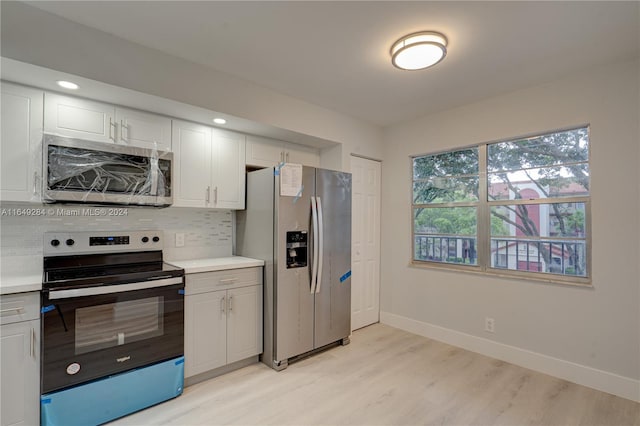 kitchen with white cabinets, appliances with stainless steel finishes, light hardwood / wood-style flooring, and decorative backsplash