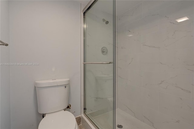 bathroom with a shower with door and toilet