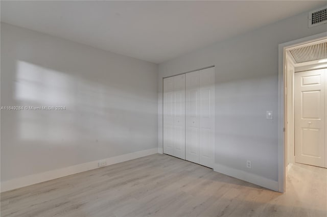 unfurnished bedroom featuring light wood-type flooring and a closet