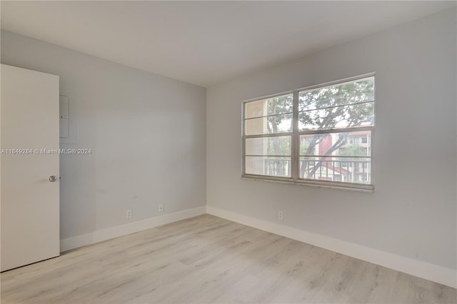 empty room with light wood-type flooring, electric panel, and plenty of natural light