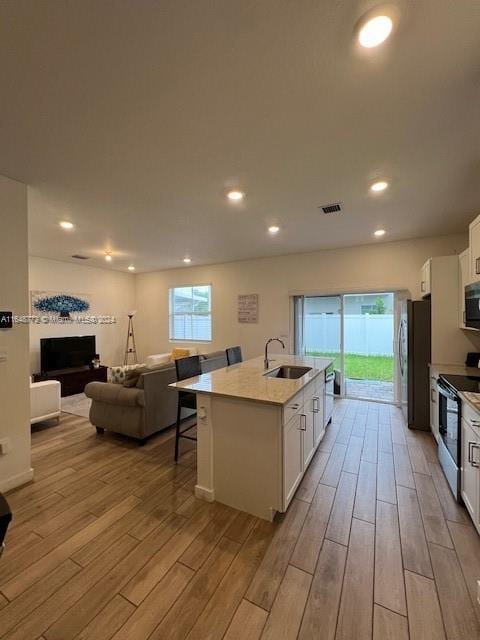 kitchen featuring sink, stainless steel appliances, light hardwood / wood-style flooring, a kitchen island with sink, and white cabinets