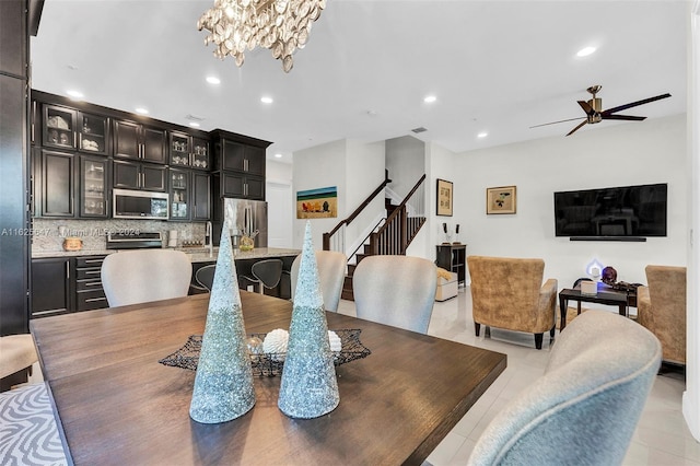 tiled dining room featuring ceiling fan with notable chandelier