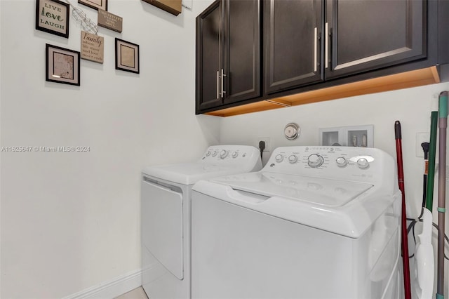 clothes washing area with cabinets and washer and clothes dryer