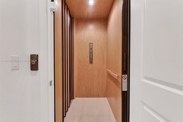 hallway featuring elevator and light tile patterned flooring