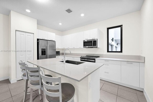 kitchen with a center island with sink, stainless steel appliances, sink, and white cabinets