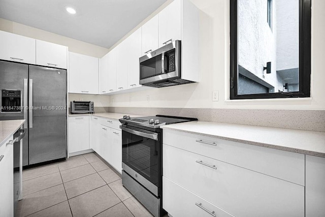 kitchen with white cabinets, light tile patterned floors, and stainless steel appliances