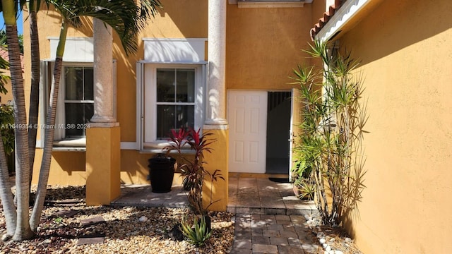 entrance to property with a tiled roof and stucco siding