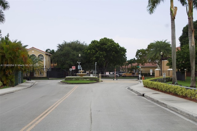 view of street with sidewalks, street lights, a gated entry, and curbs