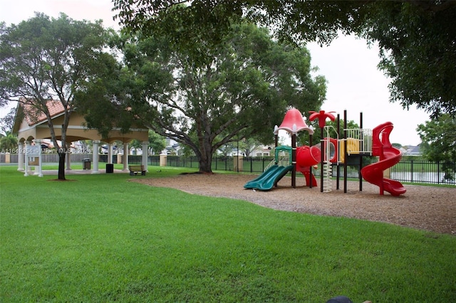 communal playground featuring a yard and fence