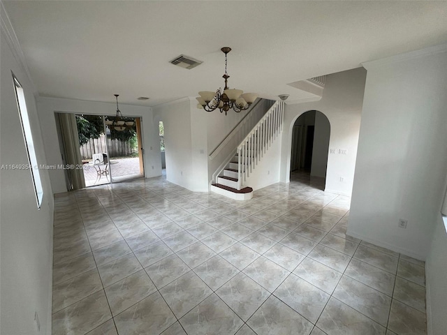 empty room with visible vents, arched walkways, a chandelier, crown molding, and stairway