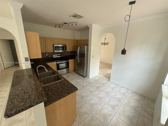 kitchen featuring track lighting, stainless steel appliances, kitchen peninsula, sink, and decorative backsplash