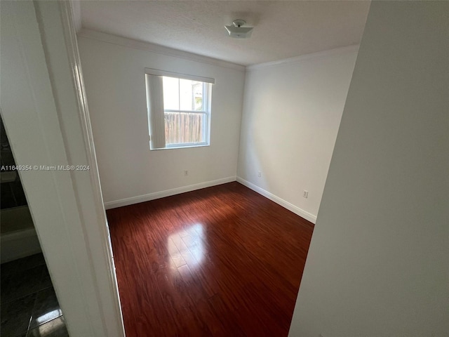 empty room with ornamental molding and dark hardwood / wood-style flooring