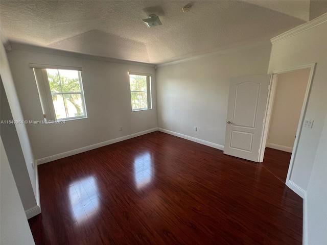 spare room featuring dark hardwood / wood-style floors, ornamental molding, and a textured ceiling