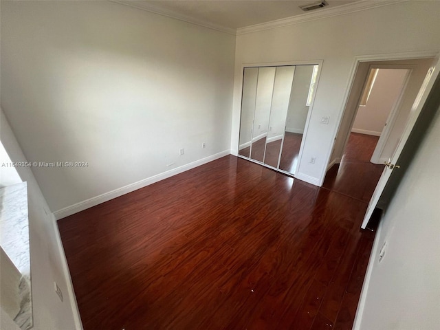 unfurnished bedroom featuring ornamental molding, dark wood-type flooring, and a closet