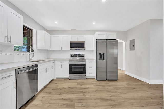 kitchen with light wood-type flooring, appliances with stainless steel finishes, sink, and white cabinets