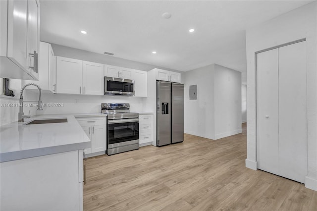 kitchen featuring stainless steel appliances, sink, white cabinets, and light hardwood / wood-style floors