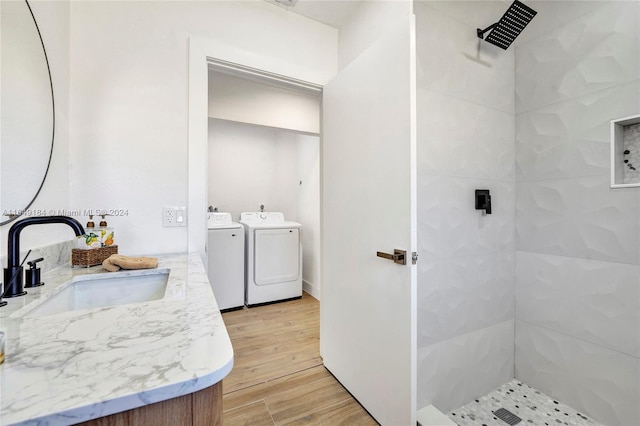 bathroom with washer and dryer, vanity, tiled shower, and hardwood / wood-style floors