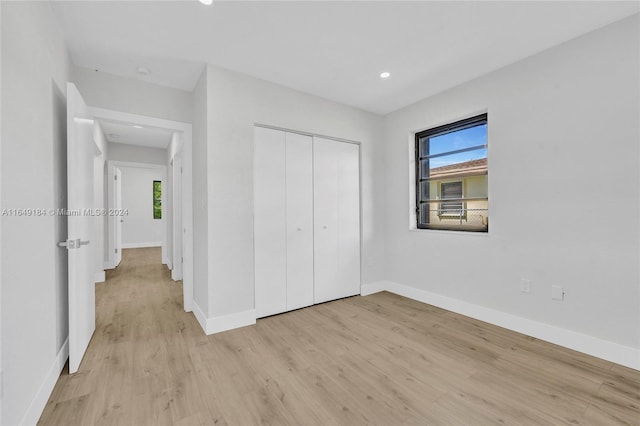 unfurnished bedroom featuring light wood-type flooring, multiple windows, and a closet