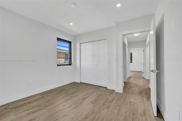 unfurnished bedroom with a closet and light hardwood / wood-style floors