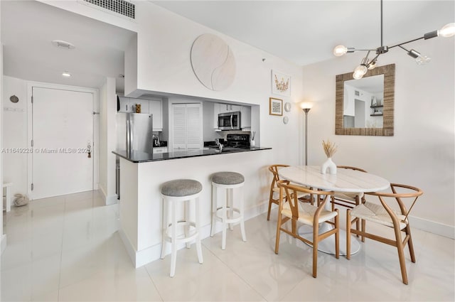 kitchen featuring kitchen peninsula, light tile patterned floors, stainless steel appliances, and decorative light fixtures