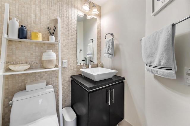 bathroom with toilet, tile walls, vanity, and tasteful backsplash