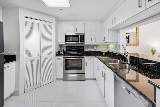 kitchen featuring stainless steel appliances, sink, light tile patterned floors, and white cabinetry