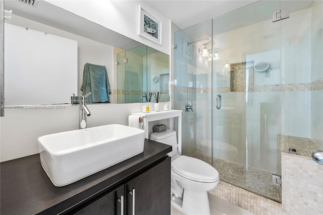 bathroom featuring vanity, toilet, and a shower with shower door