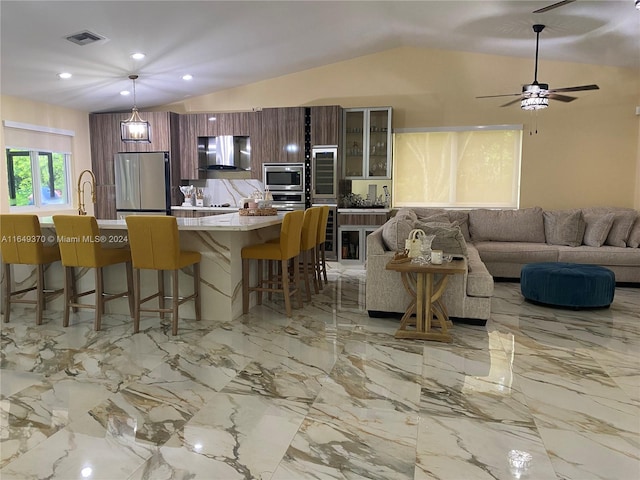 24490 SW 120th Ave, Homestead, FL 33032 - kitchen featuring stainless steel appliances, a breakfast bar, wall chimney exhaust hood, lofted ceiling, and light countertops