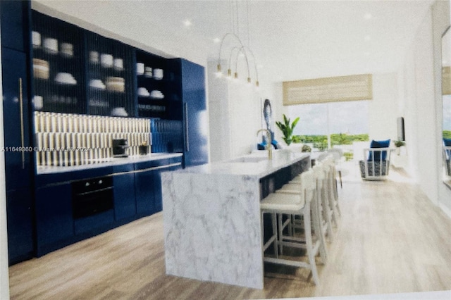 bar featuring light hardwood / wood-style flooring, light stone counters, and sink