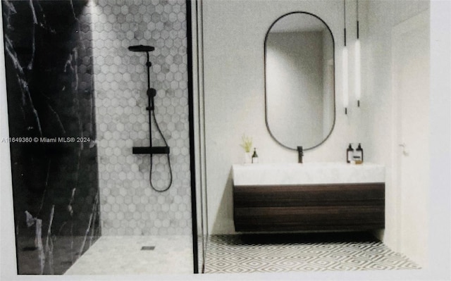 bathroom featuring tile patterned flooring, vanity, and a tile shower