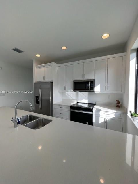 kitchen with sink, appliances with stainless steel finishes, and white cabinets