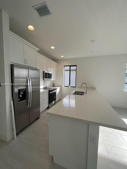 kitchen with a center island, appliances with stainless steel finishes, white cabinetry, sink, and light tile patterned flooring