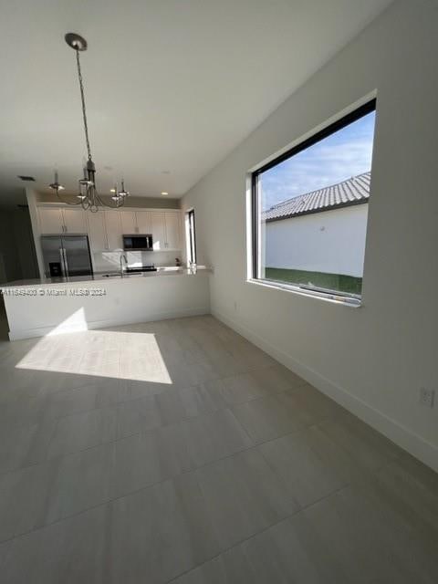 unfurnished living room featuring a notable chandelier and sink