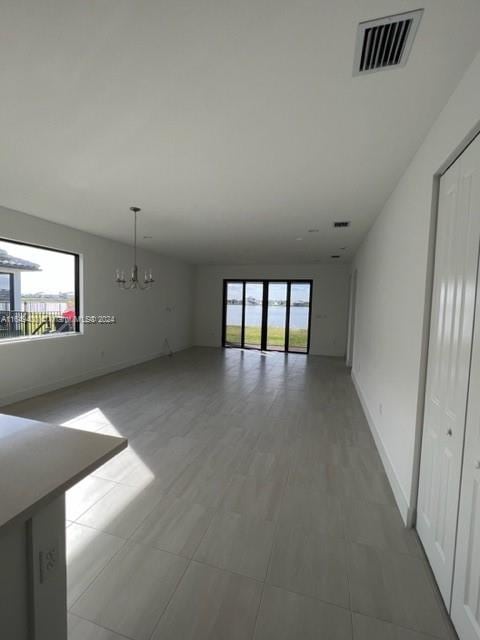 unfurnished room with a wealth of natural light and a notable chandelier