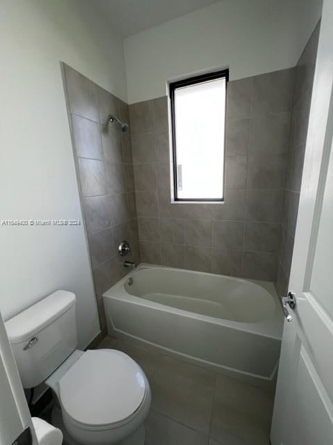 bathroom with tiled shower / bath, toilet, and tile patterned floors