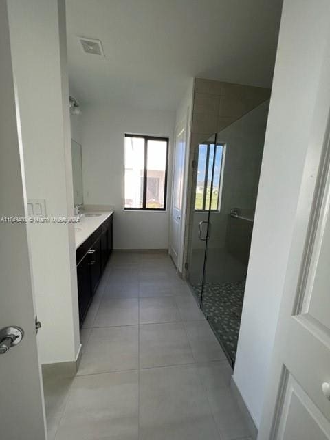 bathroom with tile patterned flooring, a shower with door, and vanity