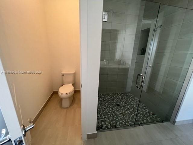 bathroom with toilet, a shower with door, and hardwood / wood-style flooring