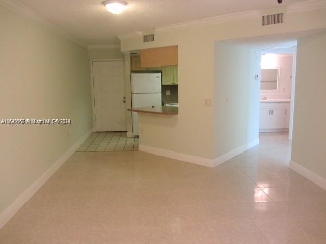 empty room with ornamental molding and light tile patterned flooring