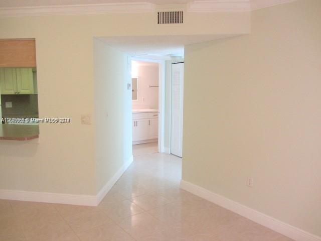 hallway with crown molding and light tile patterned floors