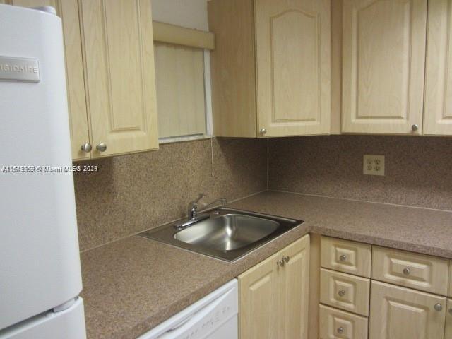 kitchen featuring light brown cabinetry, sink, white appliances, and decorative backsplash