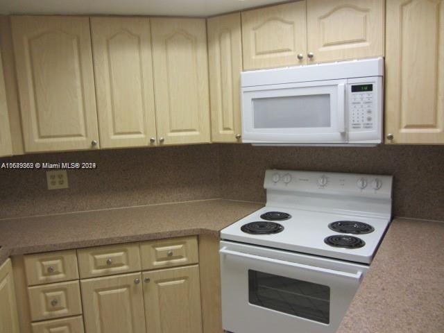 kitchen with white appliances, light brown cabinets, and decorative backsplash