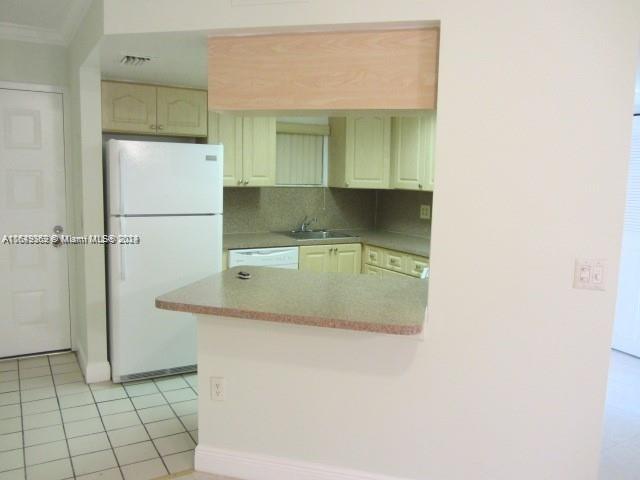 kitchen featuring backsplash, light tile patterned floors, white appliances, sink, and kitchen peninsula