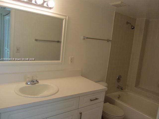 full bathroom featuring tiled shower / bath, toilet, and vanity