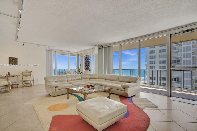 tiled living room with a textured ceiling, rail lighting, expansive windows, and a water view