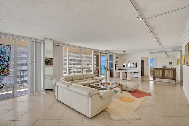 tiled living room featuring a textured ceiling, expansive windows, and track lighting