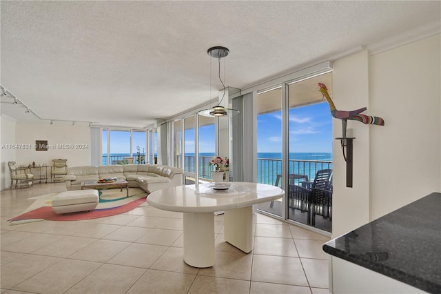 tiled dining room featuring track lighting, a textured ceiling, a water view, and expansive windows