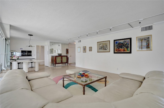 living room featuring a textured ceiling, crown molding, light tile patterned flooring, and track lighting