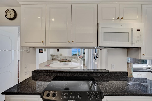 kitchen featuring range, dark stone countertops, and white cabinets