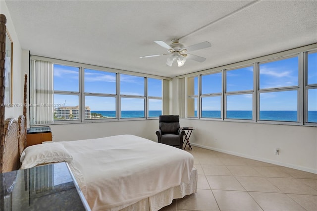 tiled bedroom with a water view, ceiling fan, and a textured ceiling