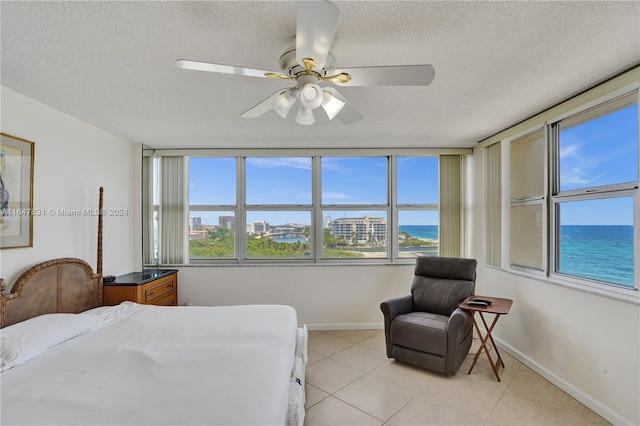 tiled bedroom with a textured ceiling, a water view, and ceiling fan